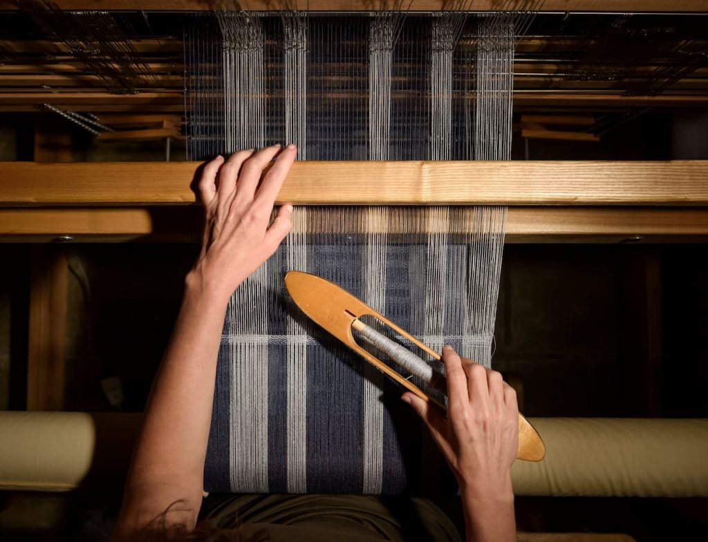 Hands weaving on a traditional wooden loom at Ana & Francis Tejedores atelier